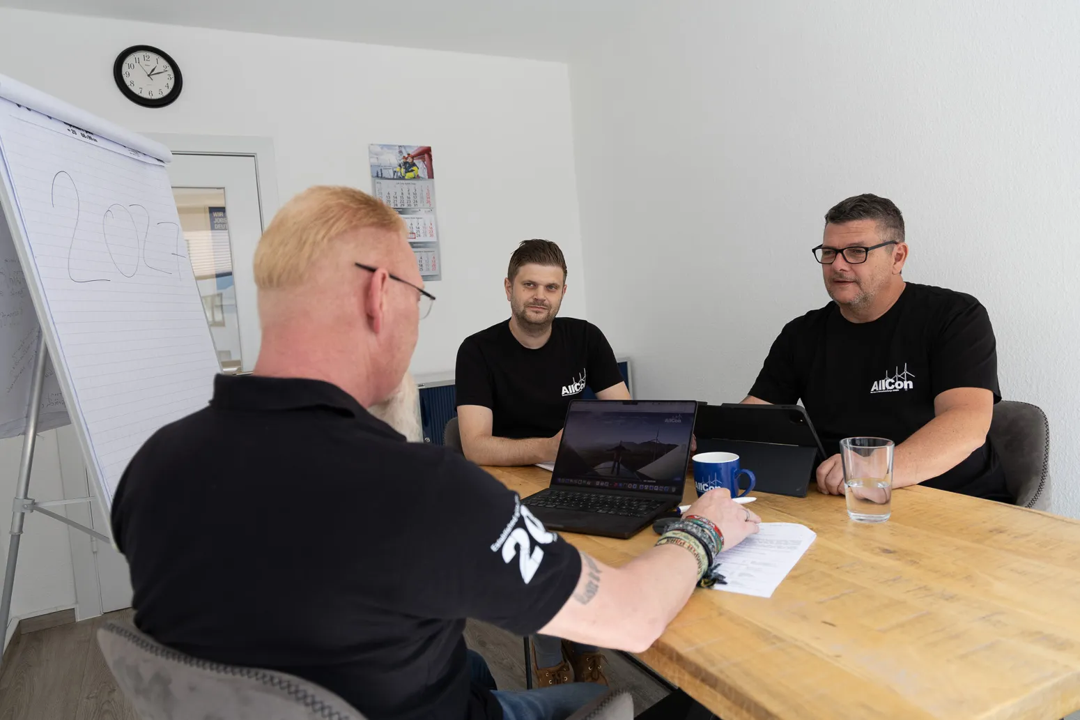 Planungsrunde zu dritt am Tisch mit Flipchart und Laptop